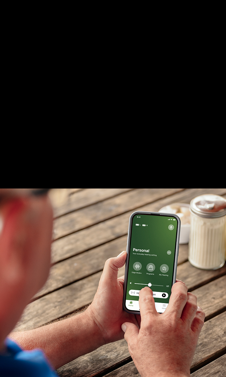 Man adjusting the volume of his hearing aids with the My Audibel app.