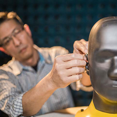Man fitting a hearing aid on a mannequin head