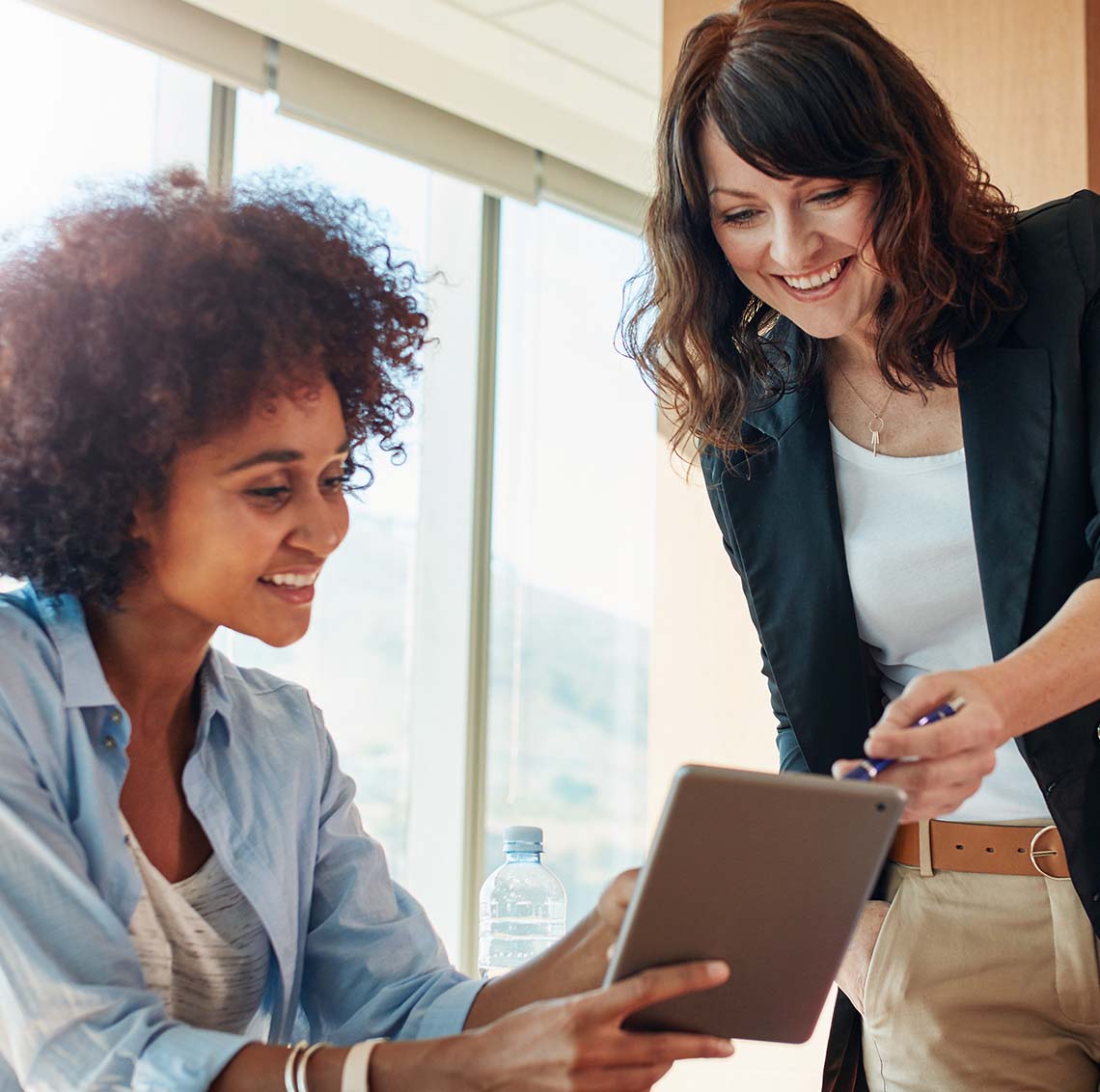 Smiling people looking at a tablet