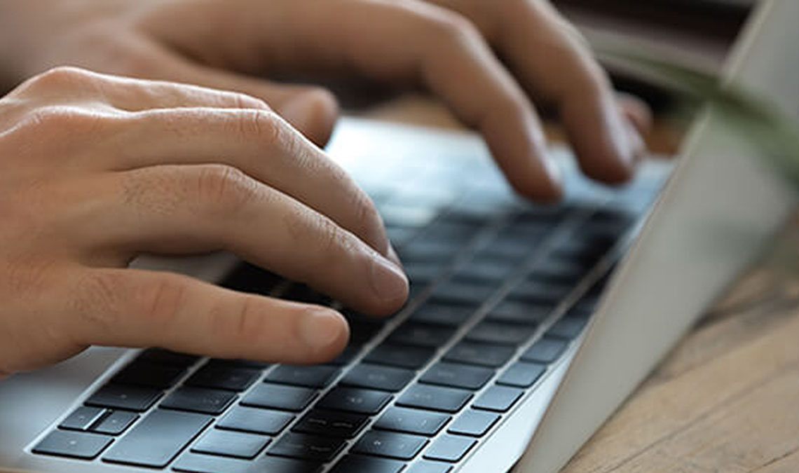 Hands typing on a laptop keyboard