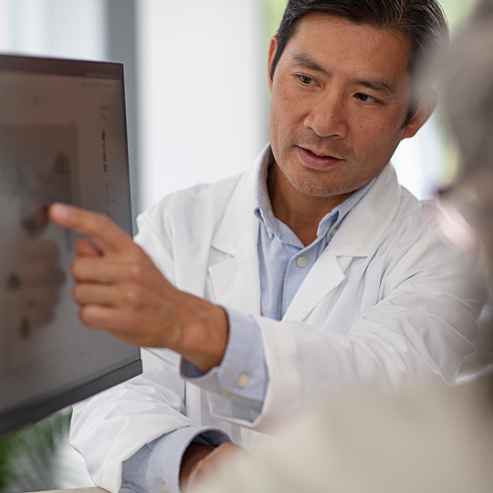 Audiologist pointing at software on a computer screen.