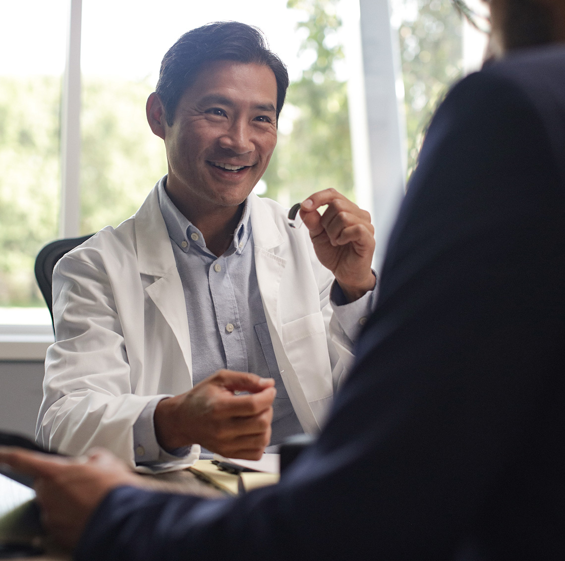 Professional holding hearing aid in front of patient