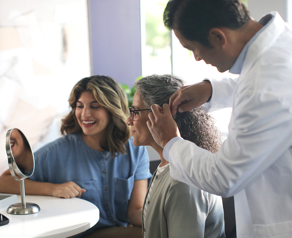 Professional fitting a patient with hearing aid